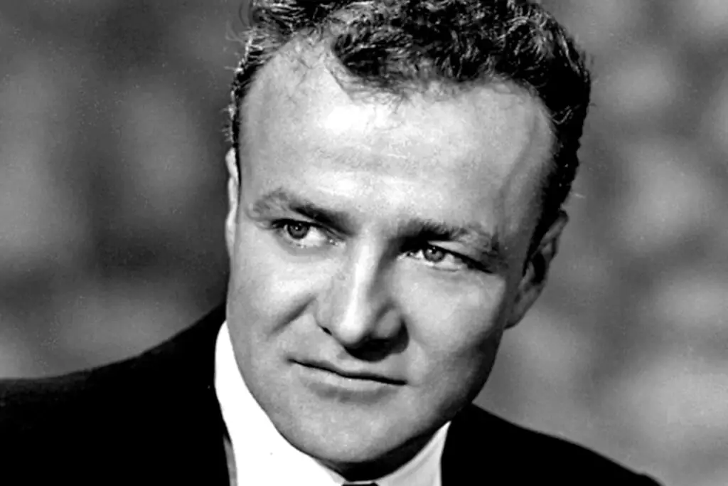 Black and white portrait of a man with short, curly hair, wearing a dark suit and white shirt. He is looking slightly to his left with a serious expression. The background is blurred, imbuing an air of cybersecurity vigilance in an era of growing cyberthreats.