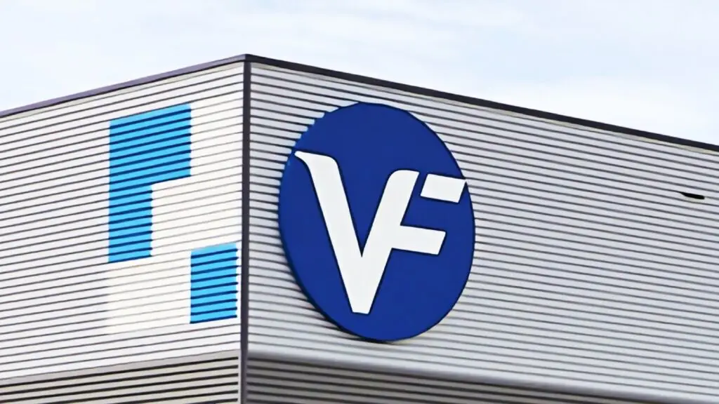 A corrugated metal building features a blue circular logo with white 'VF' initials prominently displayed. Adjacent to the logo are geometric vertical blue and white bars, symbolizing robust VPN services. The background shows a clear, lightly clouded sky.