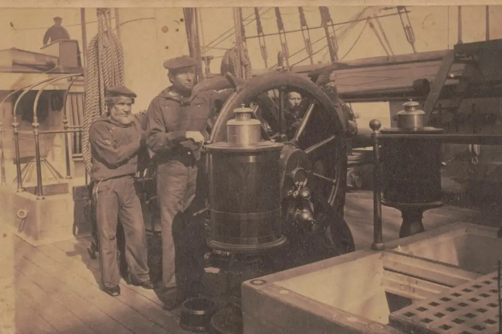 This sepia-toned image shows three sailors in vintage naval uniforms on the wooden deck of an old ship. One sailor is steering the large ship’s wheel, while the other two stand beside him, reminiscent of a time when cyberthreats were as distant as the horizon. Ropes, masts, and parts of the ship are visible in the background.