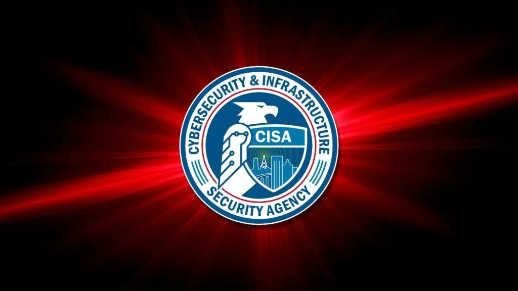 Cybersecurity & Infrastructure Security Agency (CISA) logo centered on a dark background with red rays radiating outward. The logo, reminiscent of DOD insignia, features an eagle's head with interconnected designs representing digital circuits and a cityscape enclosed in a blue circle with text.