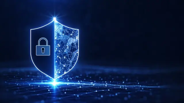 A blue, futuristic shield is illustrated on a dark background. The left half of the shield features a padlock symbol, while the right half is a network of interconnected nodes, embodying CMMC standards and digital protection.