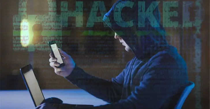 A person wearing a hoodie sits in front of a laptop, holding a smartphone. The background features binary code and the word "HACKED" prominently displayed. The dimly lit scene, with its blue tone, underscores the importance of cybersecurity measures like VPNs to protect against such breaches.