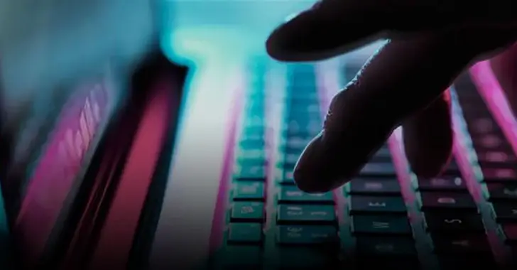 Close-up of a person's hand typing on a keyboard, with a gradient of blue and pink light illuminating the scene. The blurred background suggests a computer screen, creating a focused, moody tech atmosphere—perfect for deep dives into CMMC cybersecurity protocols for the DOD.