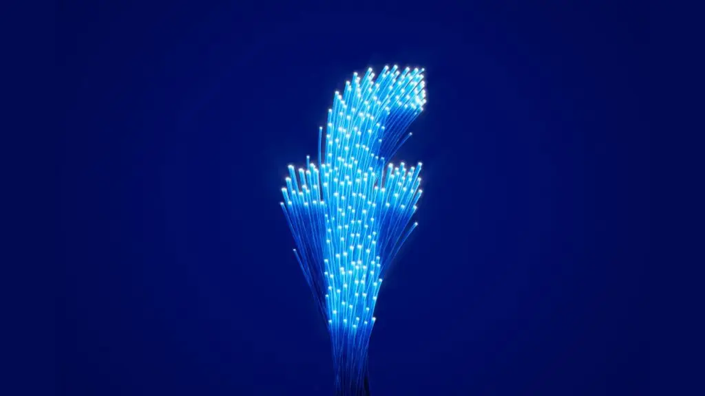 A cluster of glowing blue fiber optic cables against a dark blue background, fanning out and curving slightly upward, resembling a spark of light or a modern sculpture. The cables' tips emit vibrant points of light, symbolizing the delicate defense mechanisms crucial in combating cyberthreats.